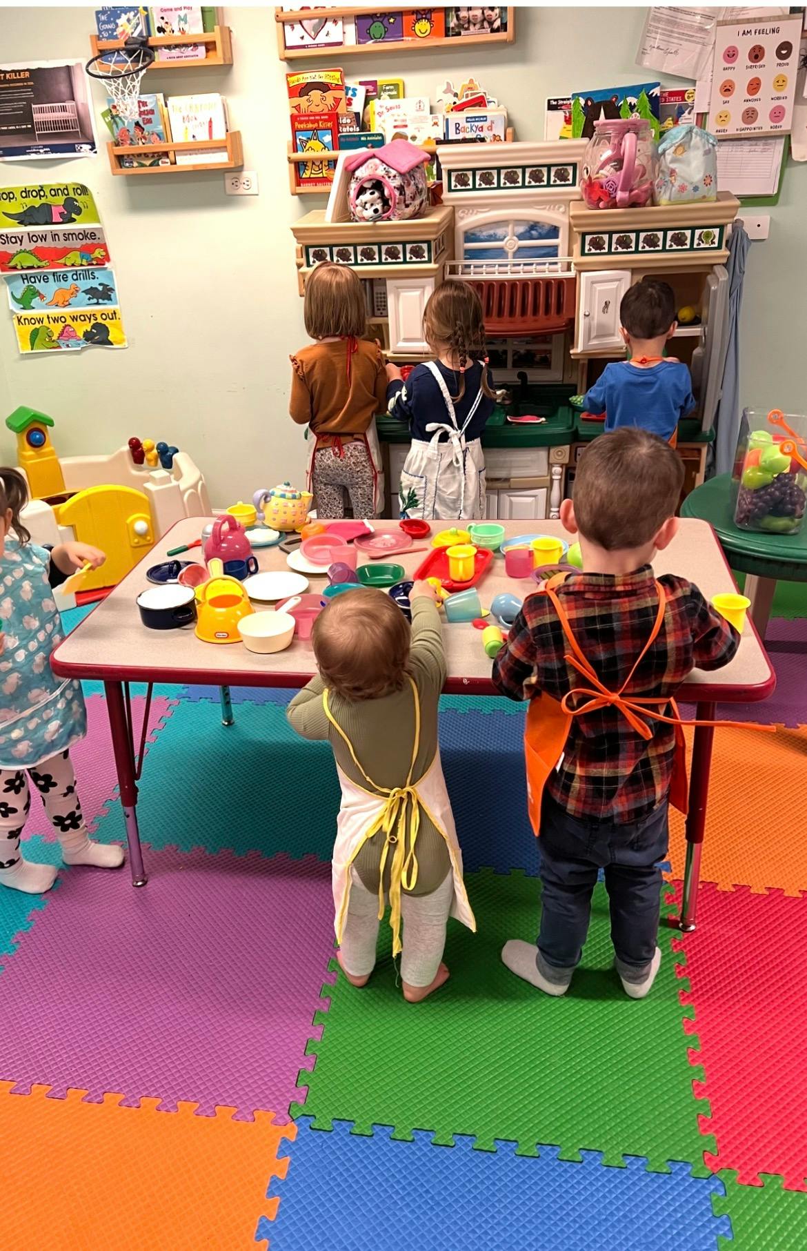 Children playing with toy kitchen sets in a classroom