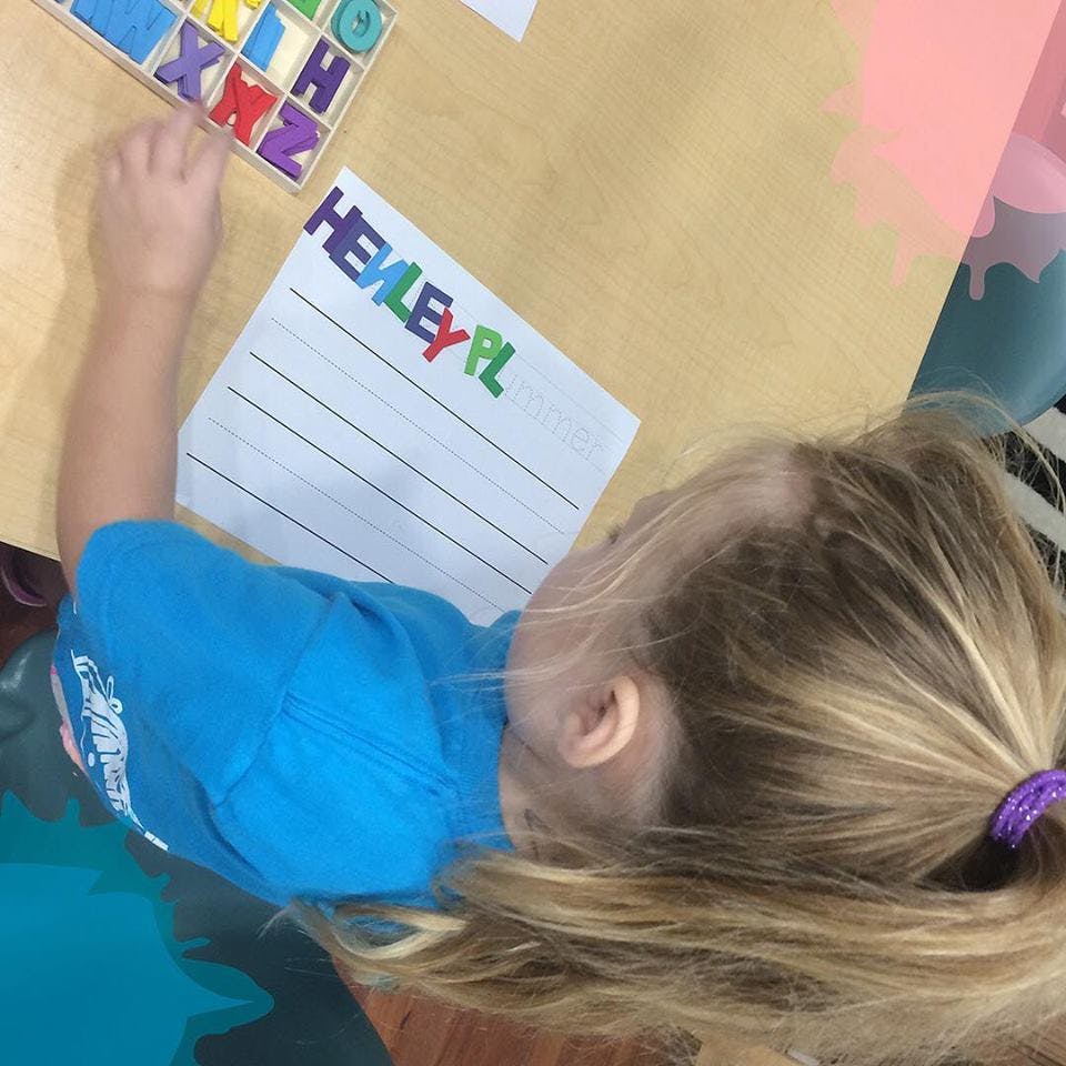 Child arranging colorful letter magnets on paper