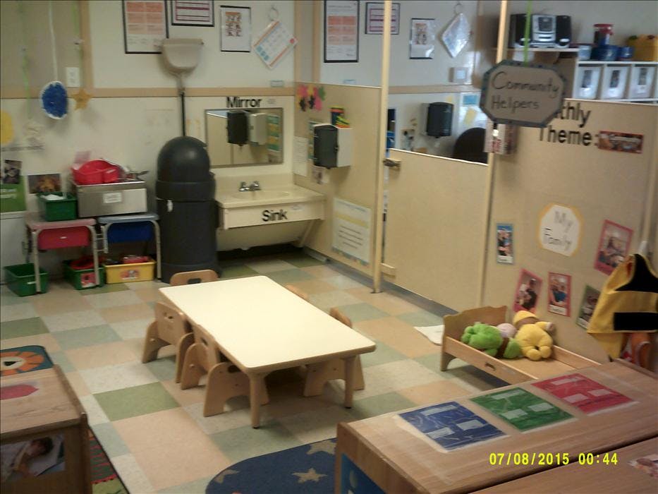 Children's classroom with small tables, chairs, sink, and bulletin board