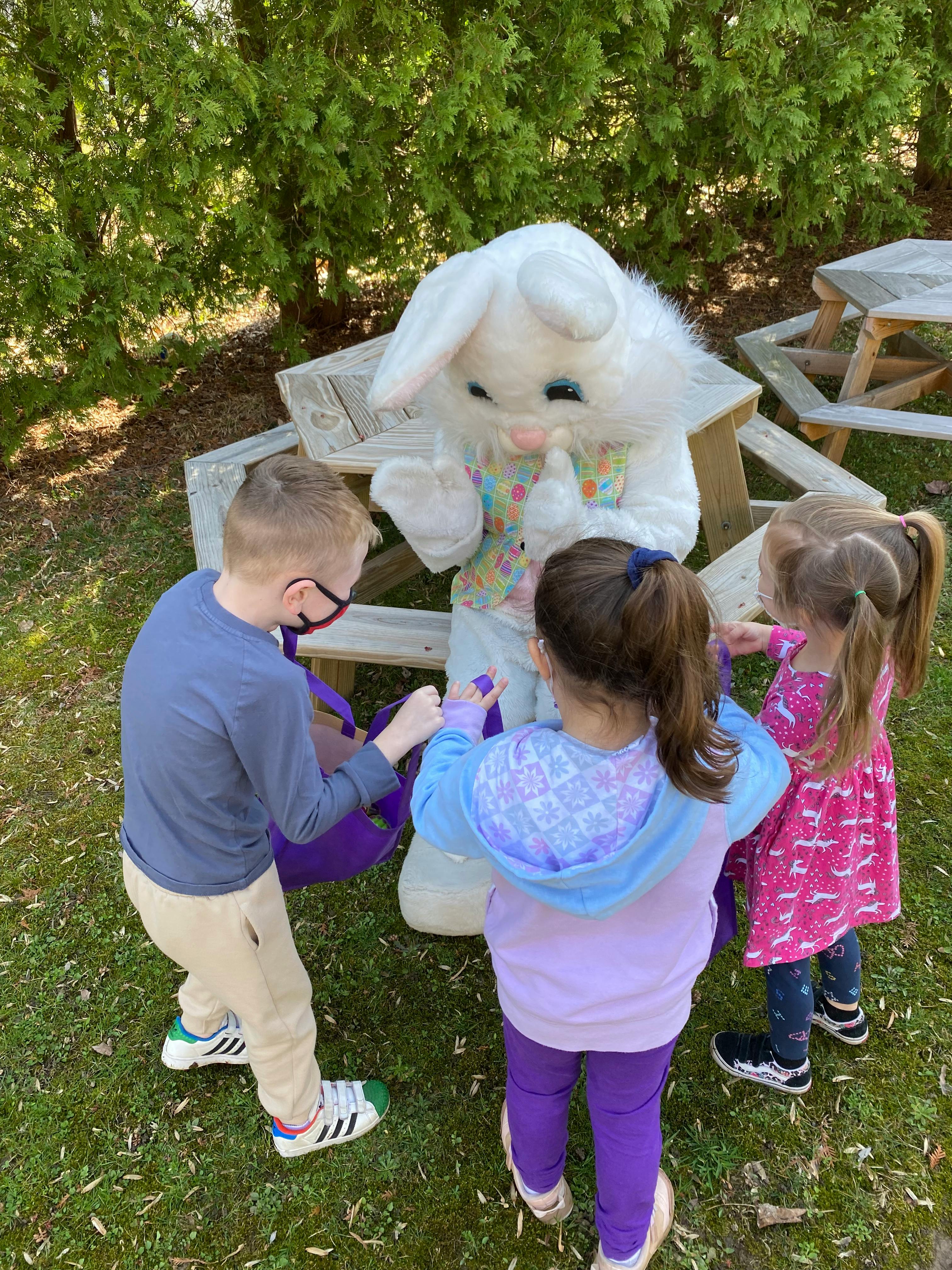 Children interacting with a person in a bunny costume outdoors