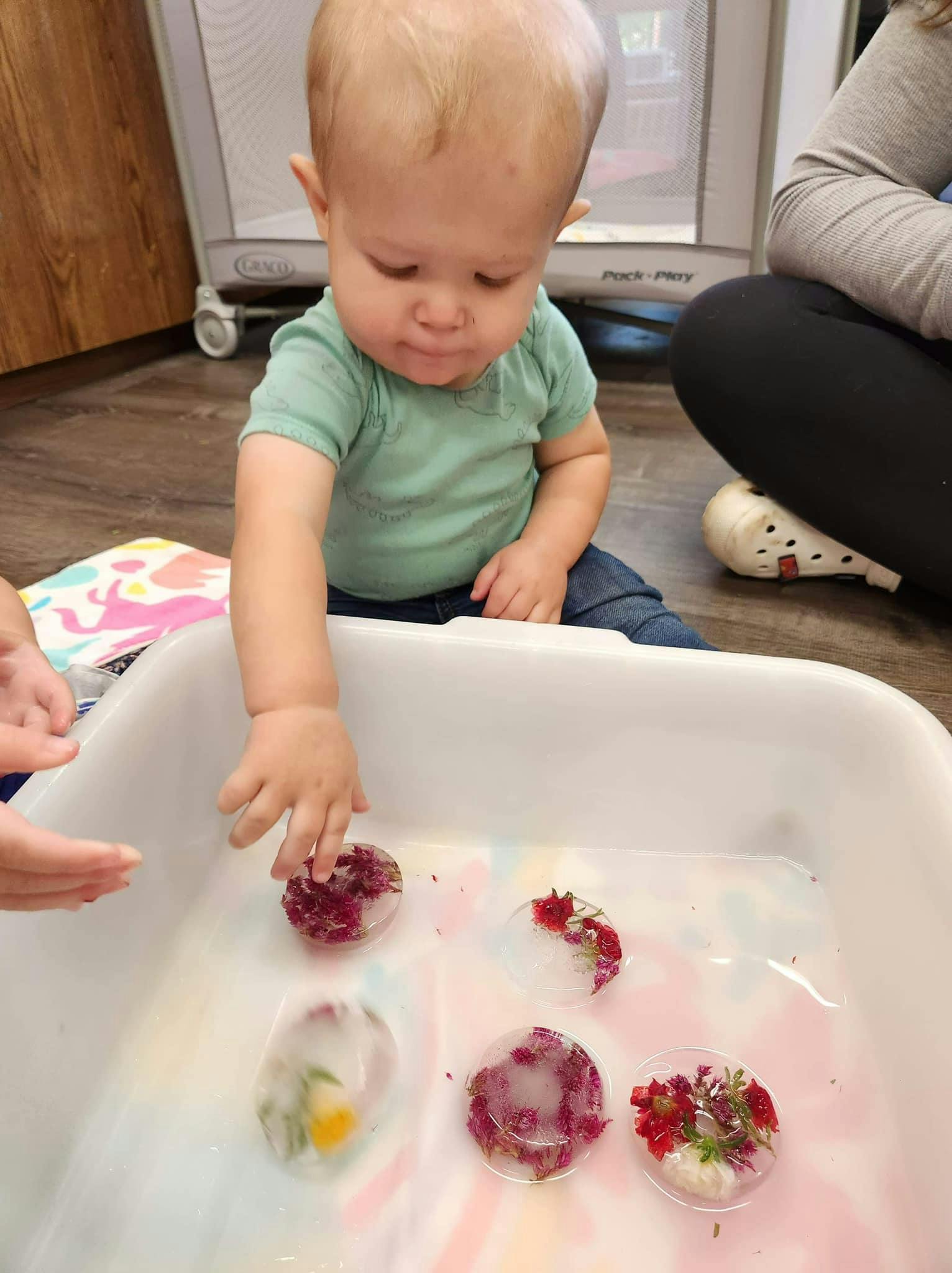 Child reaching for frozen flowers in a white bin