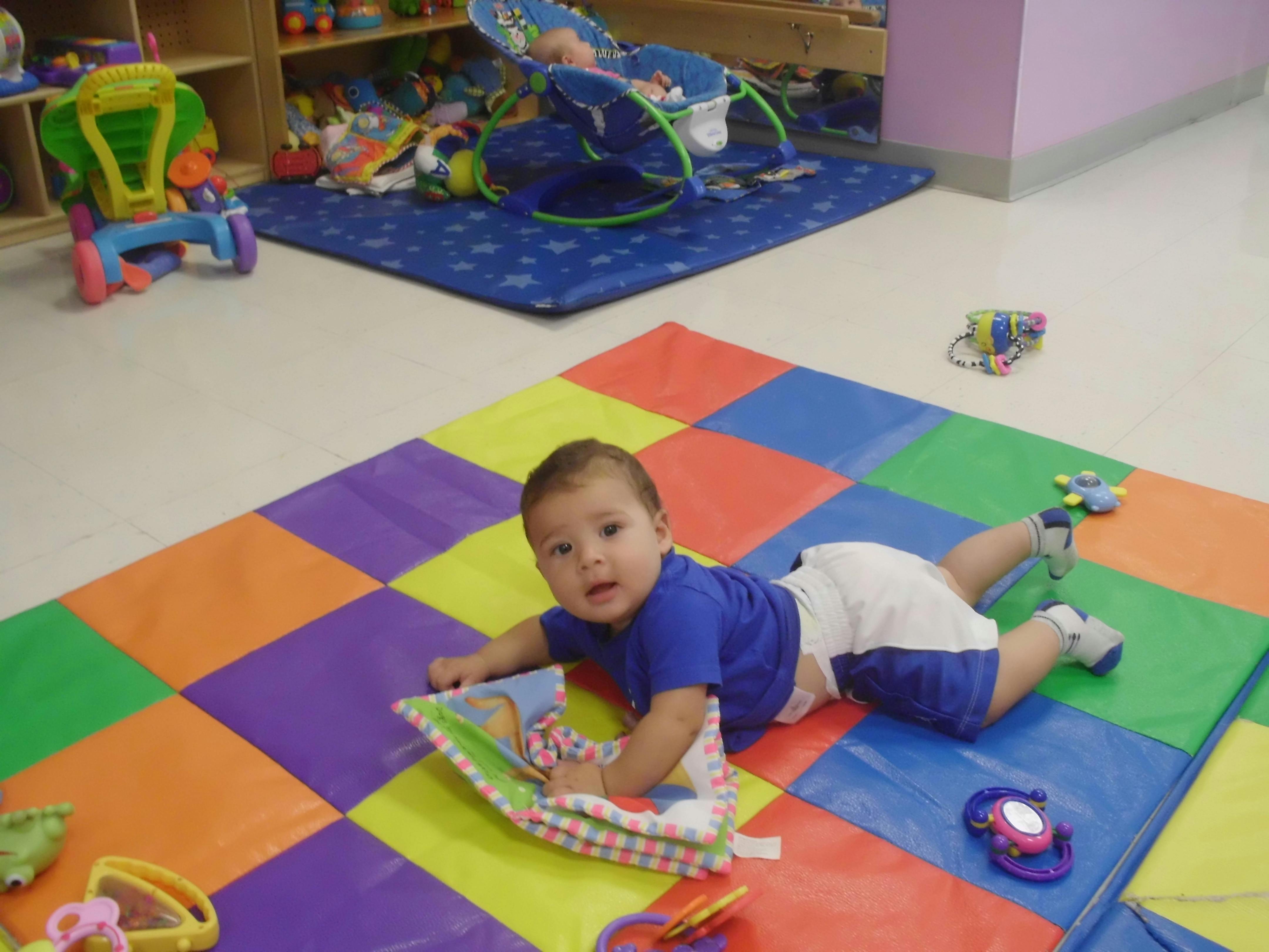 Child on stomach on colorful mat with toy