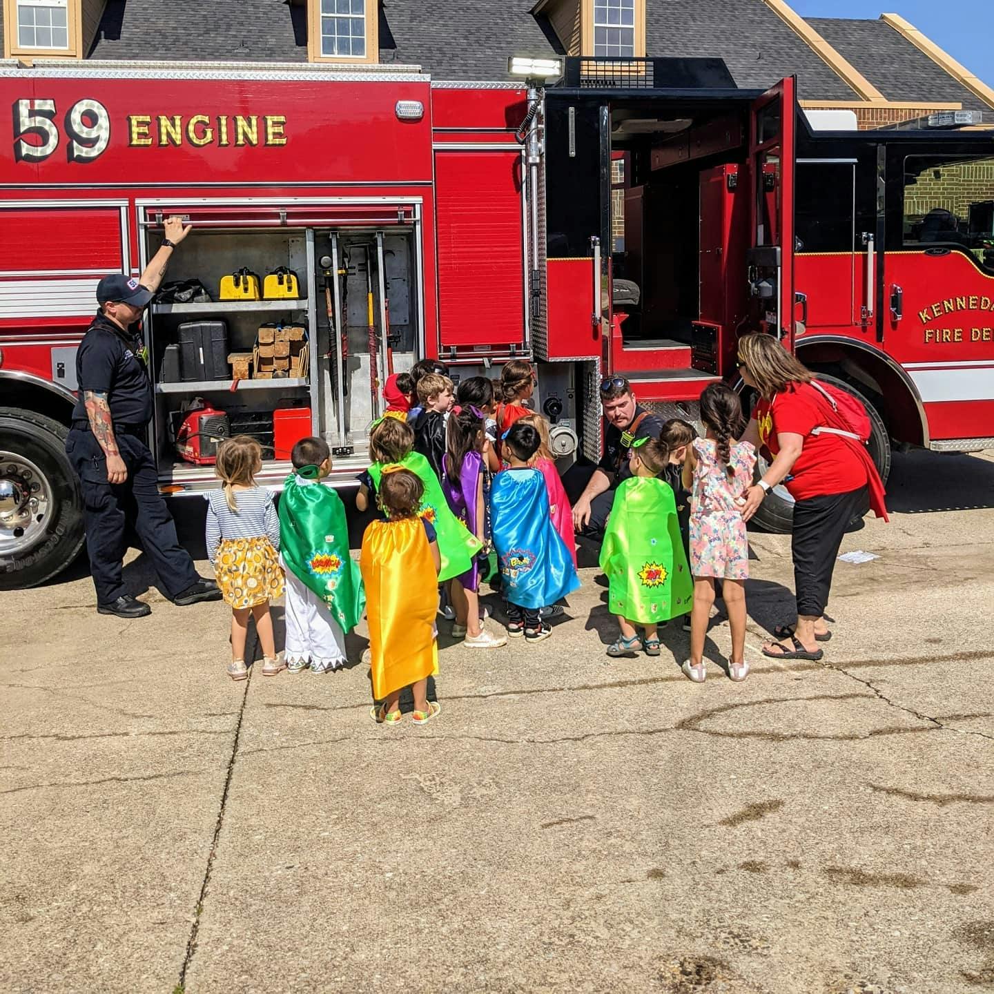 Children in capes with adults near a fire truck
