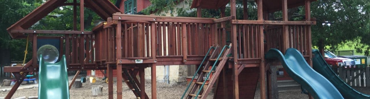 Wooden playground structure with slides and ladders