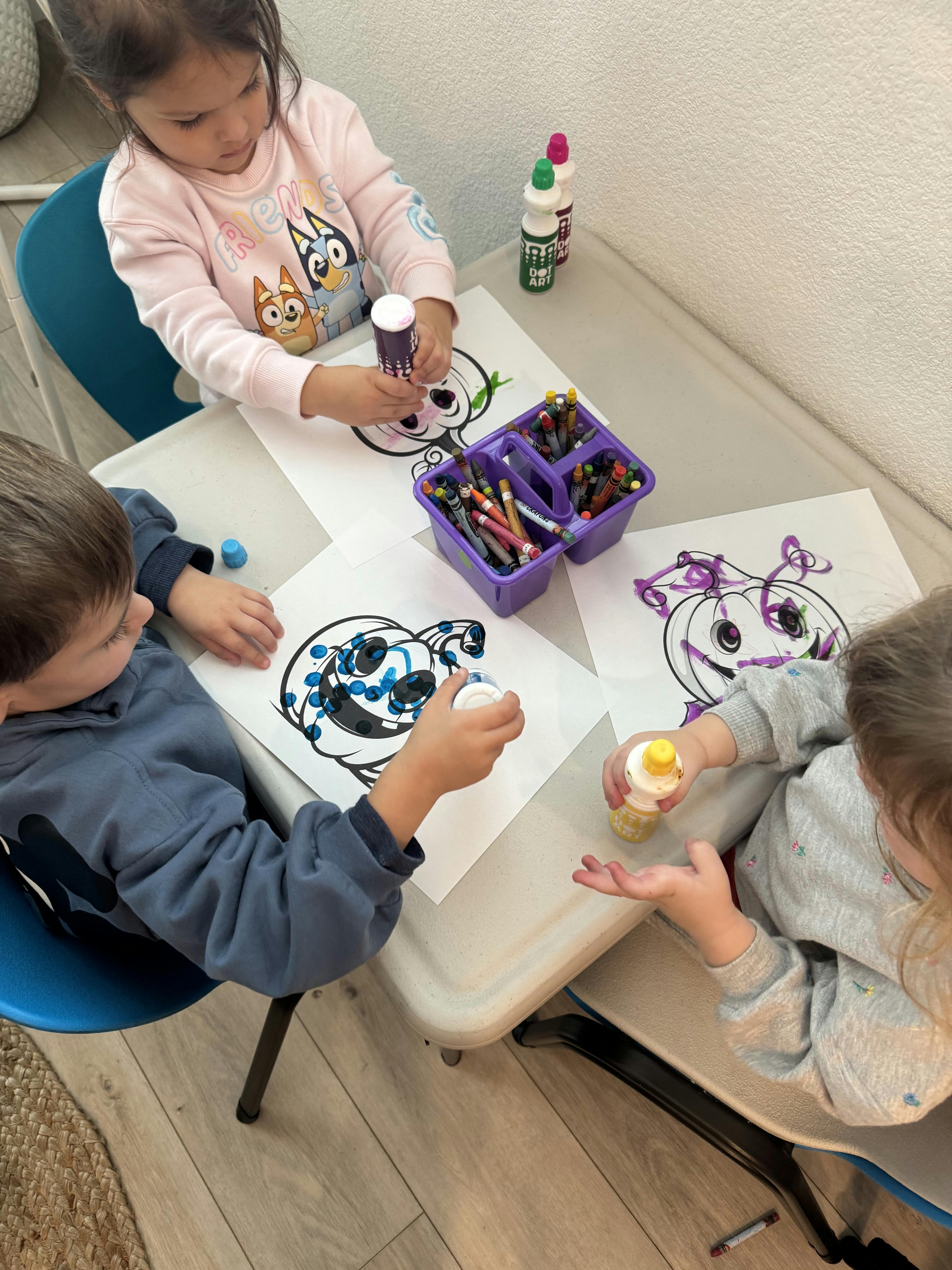 Three children sitting at a table and coloring