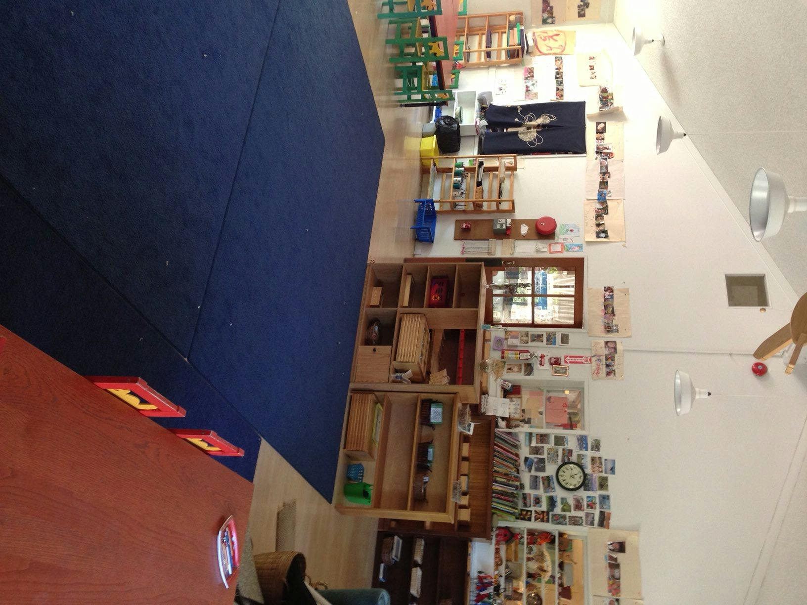 Classroom with blue mat, wooden shelves, and wall decorations