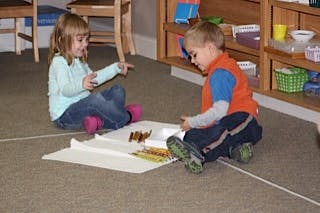 Two children sitting on floor playing with toys