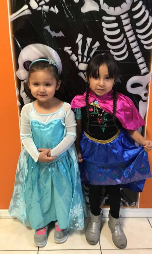 Two children in costumes standing in front of a skeleton decoration