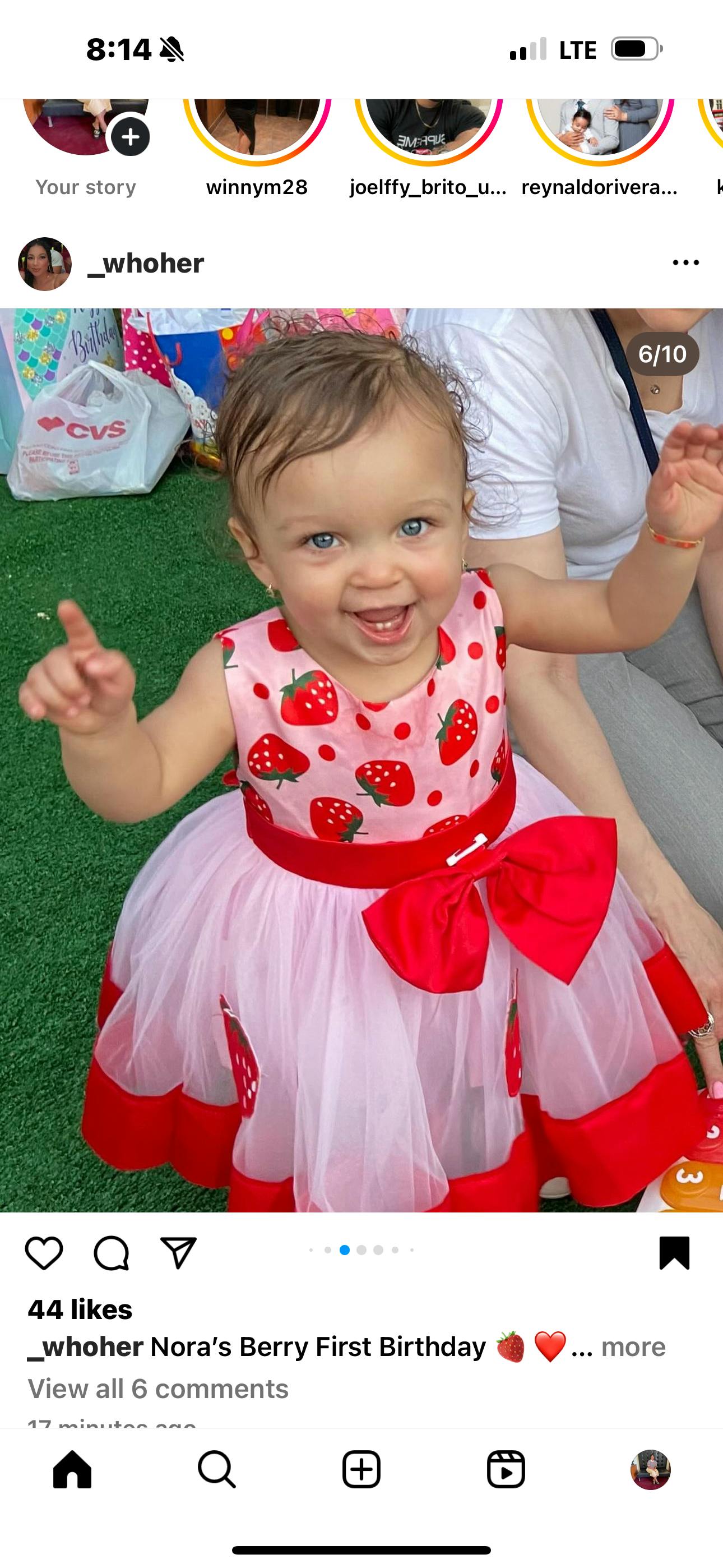 Child in a strawberry print dress with a red bow