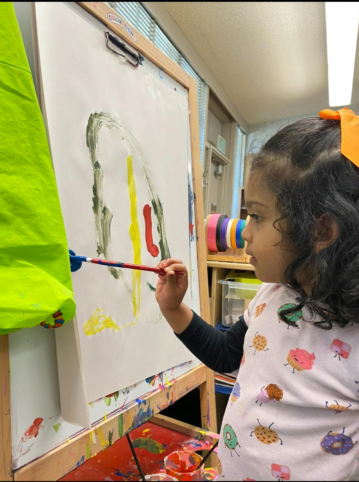 Child painting on an easel in a classroom