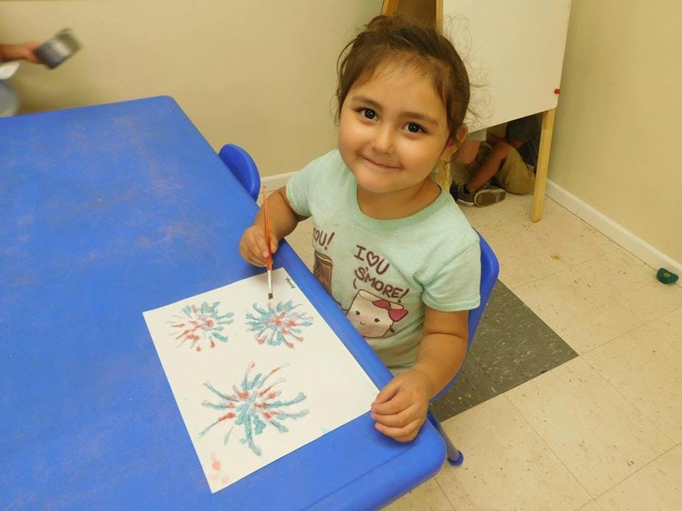 Child painting on paper at a blue table