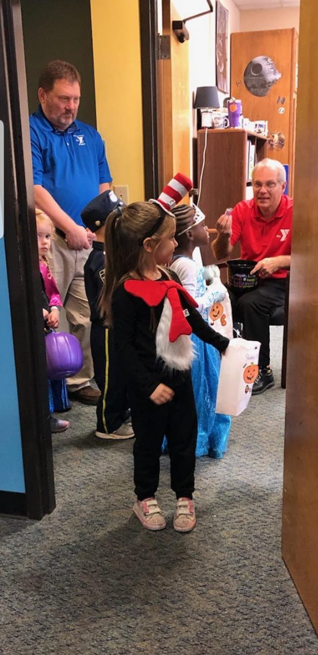 Children in costumes trick-or-treating from an adult