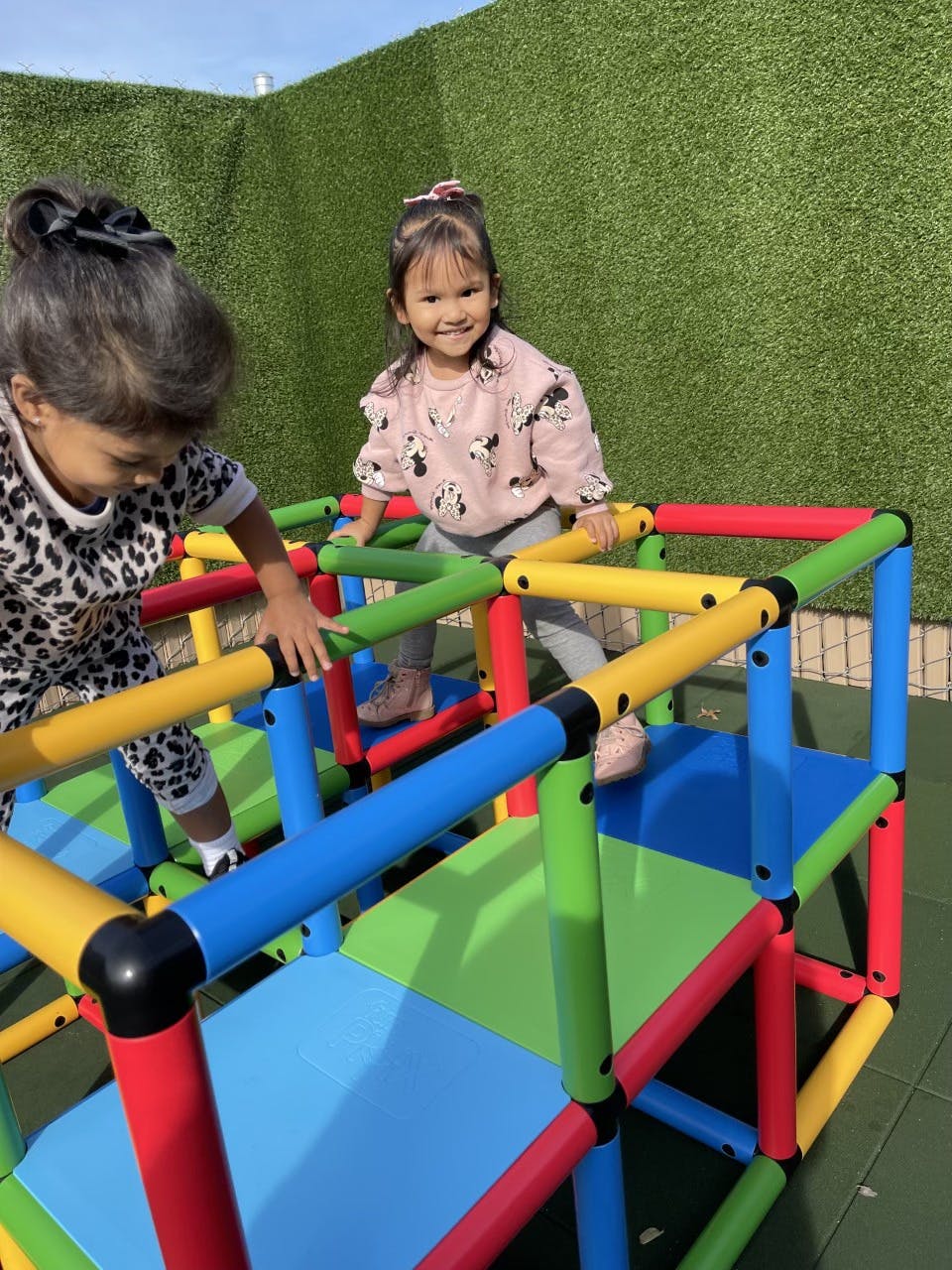 Two children playing on a colorful climbing structure