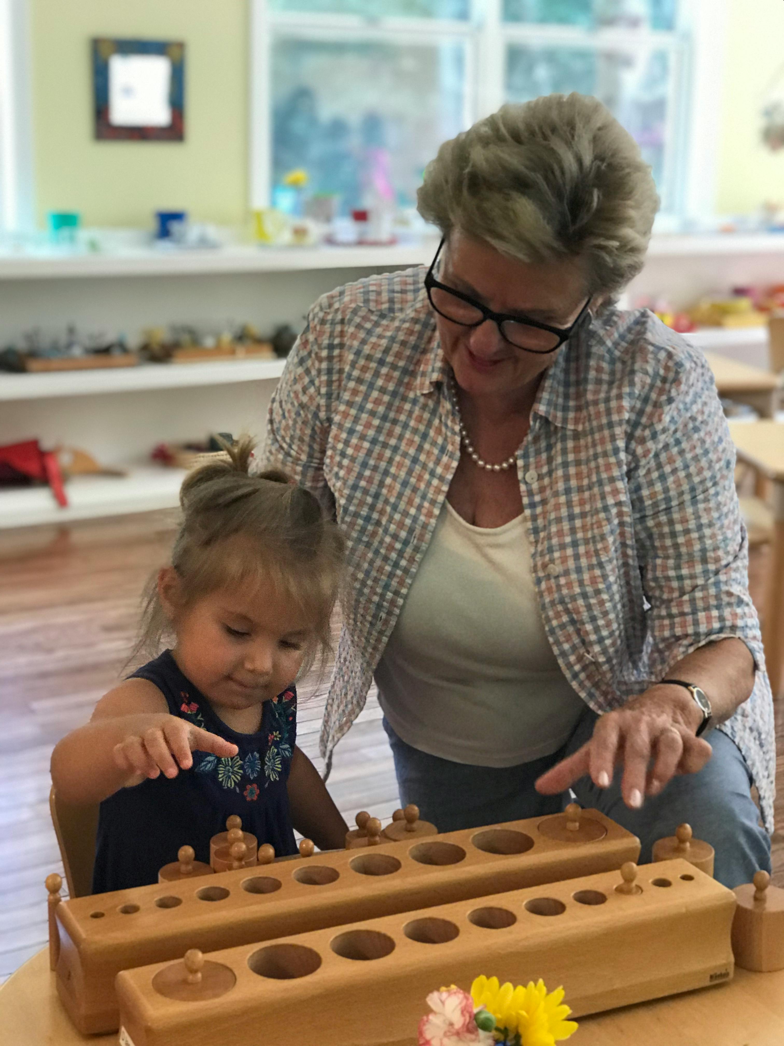 Adult and child playing with wooden cylinder blocks
