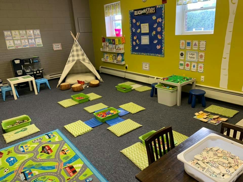 Playroom with a teepee, small tables, and floor cushions