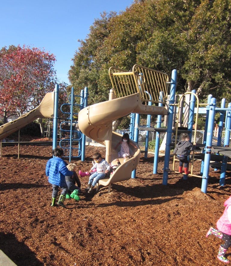 Children playing on a playground with slides and climbing structures