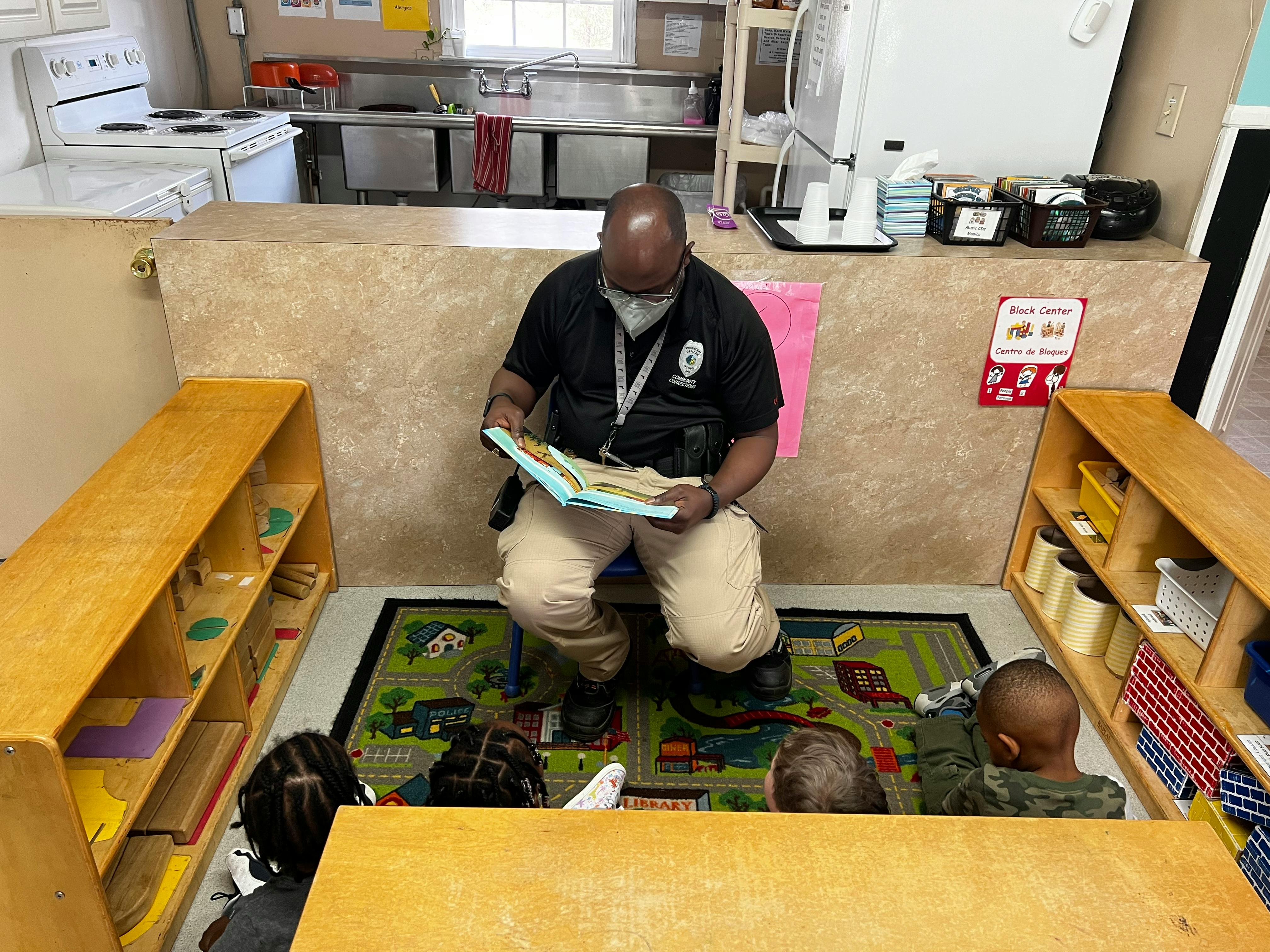 Person reading a book to children in a classroom