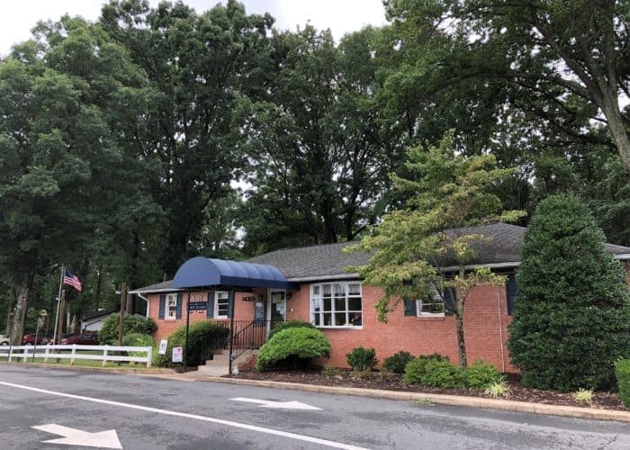 Brick building with a blue awning and trees