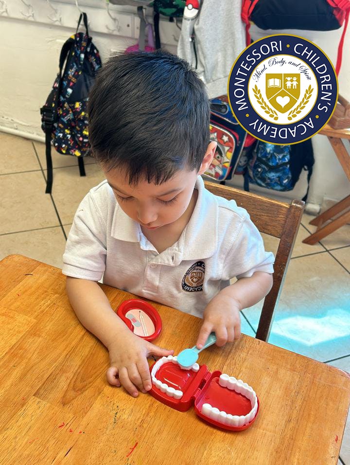 Child practicing dental hygiene on a toy set at a classroom table