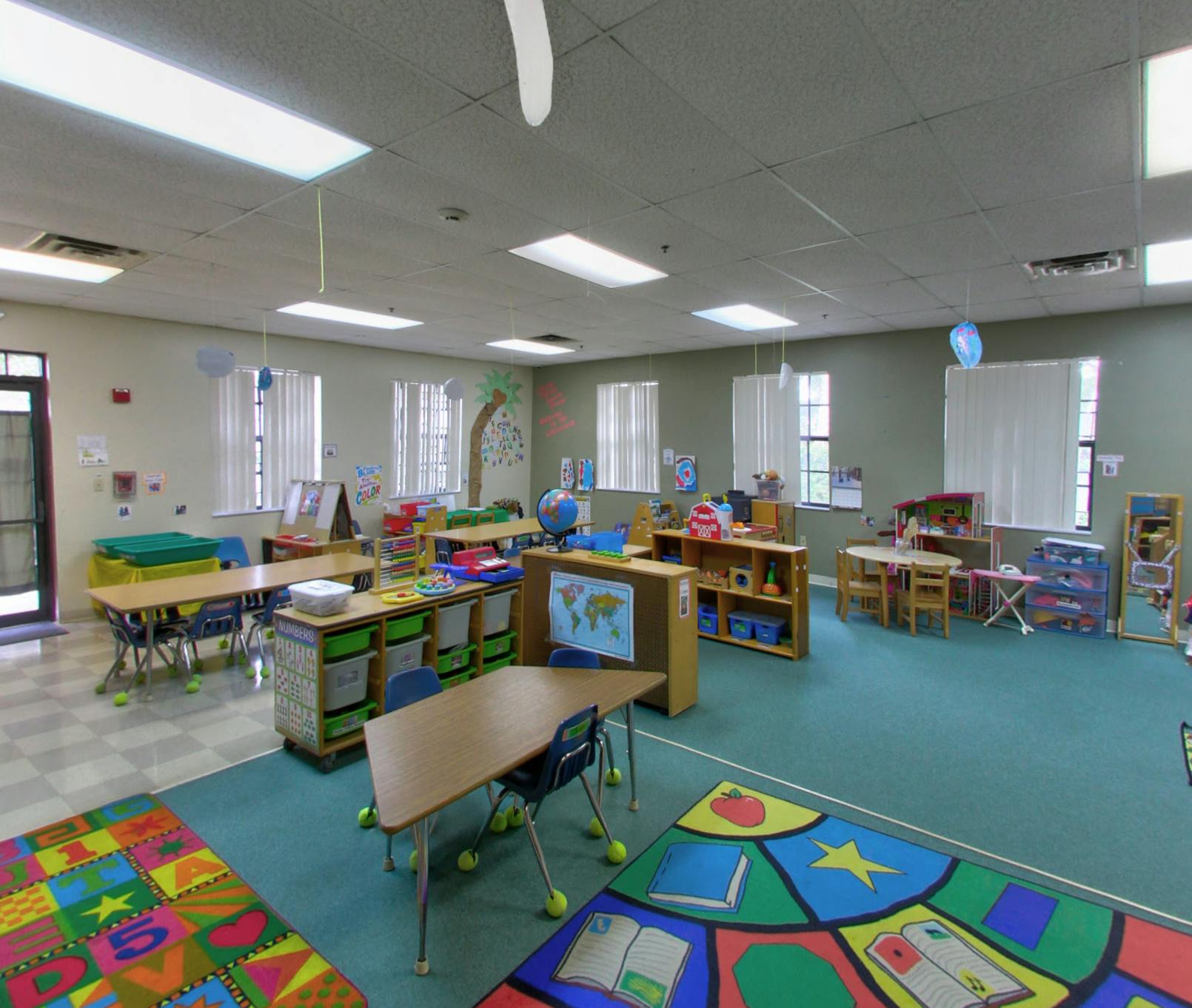 Empty classroom with small tables, chairs, and colorful rugs