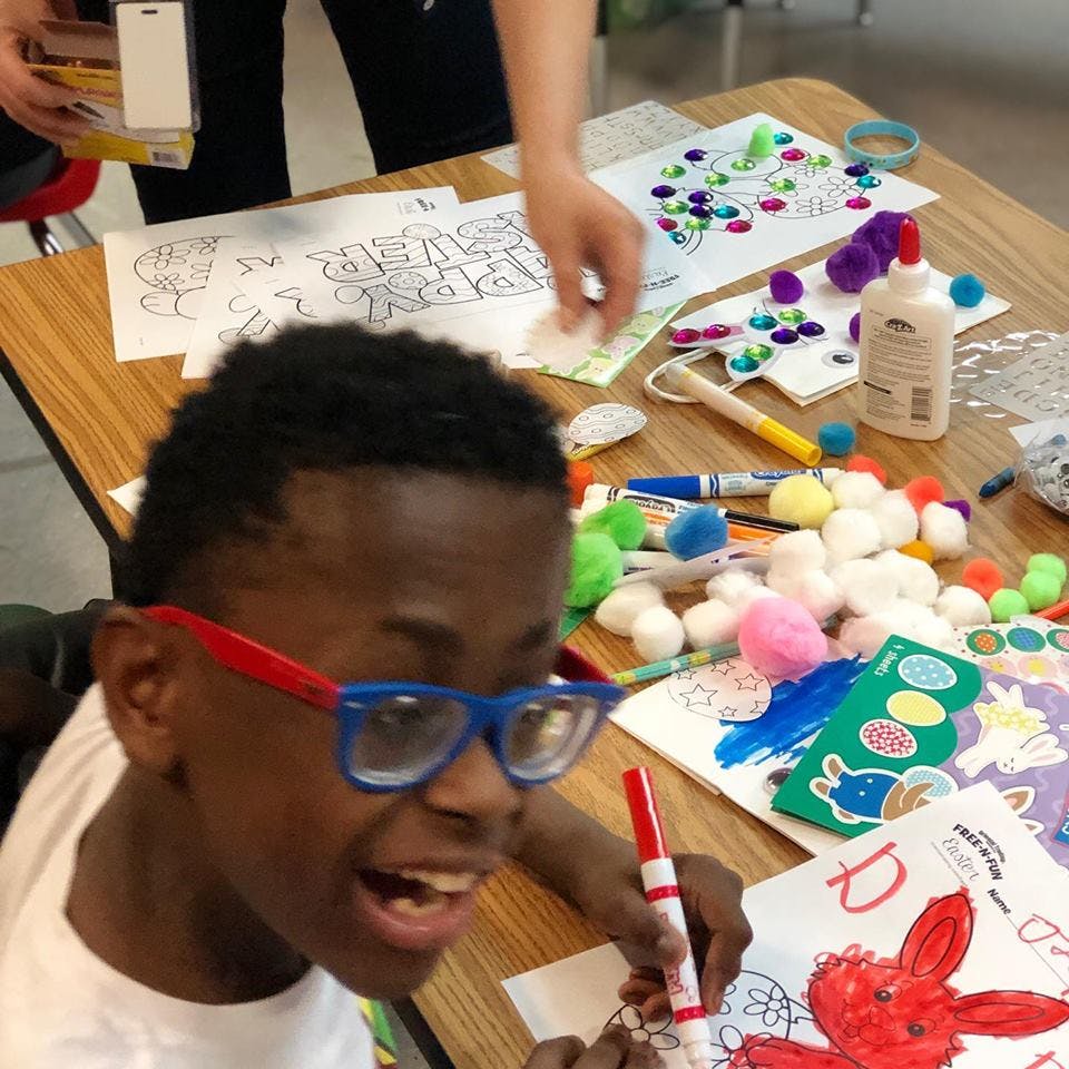 Child in glasses coloring at a table with craft supplies