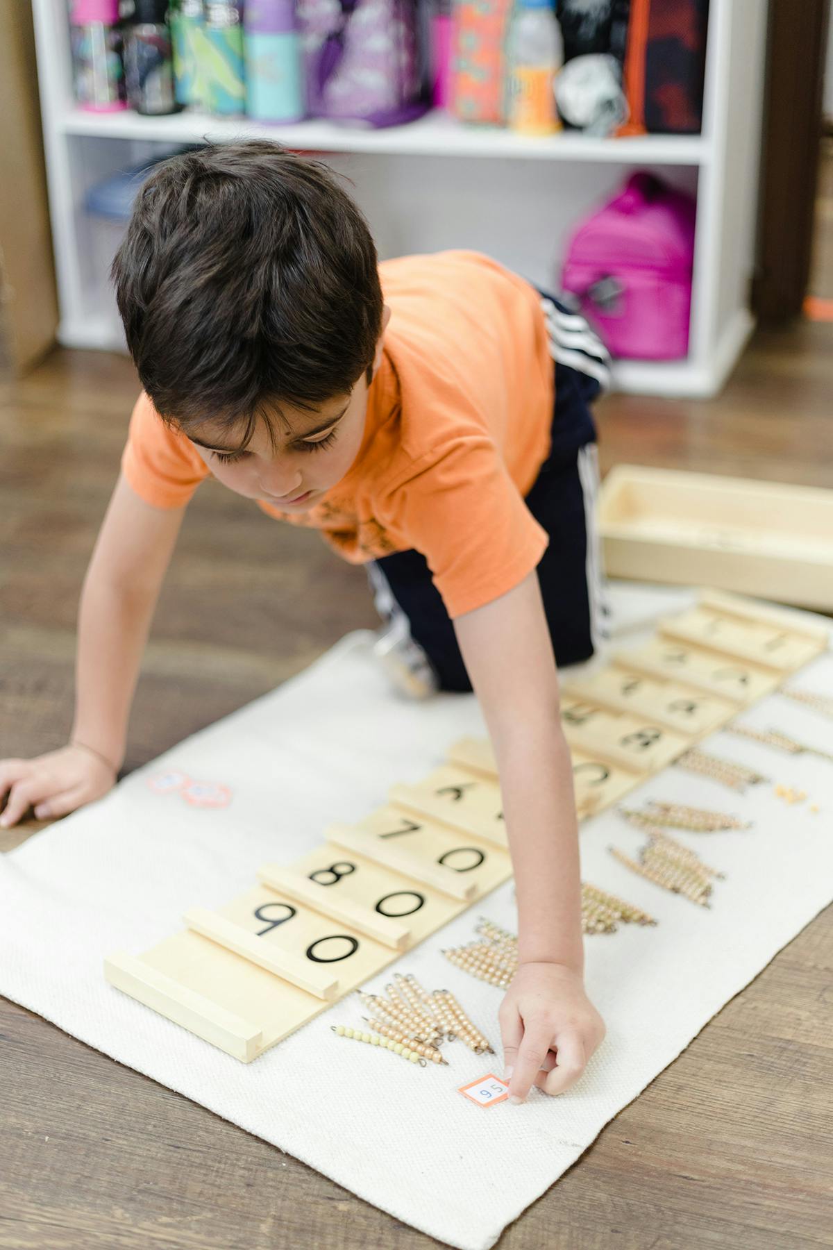 Child on floor working with number blocks and small counting sticks