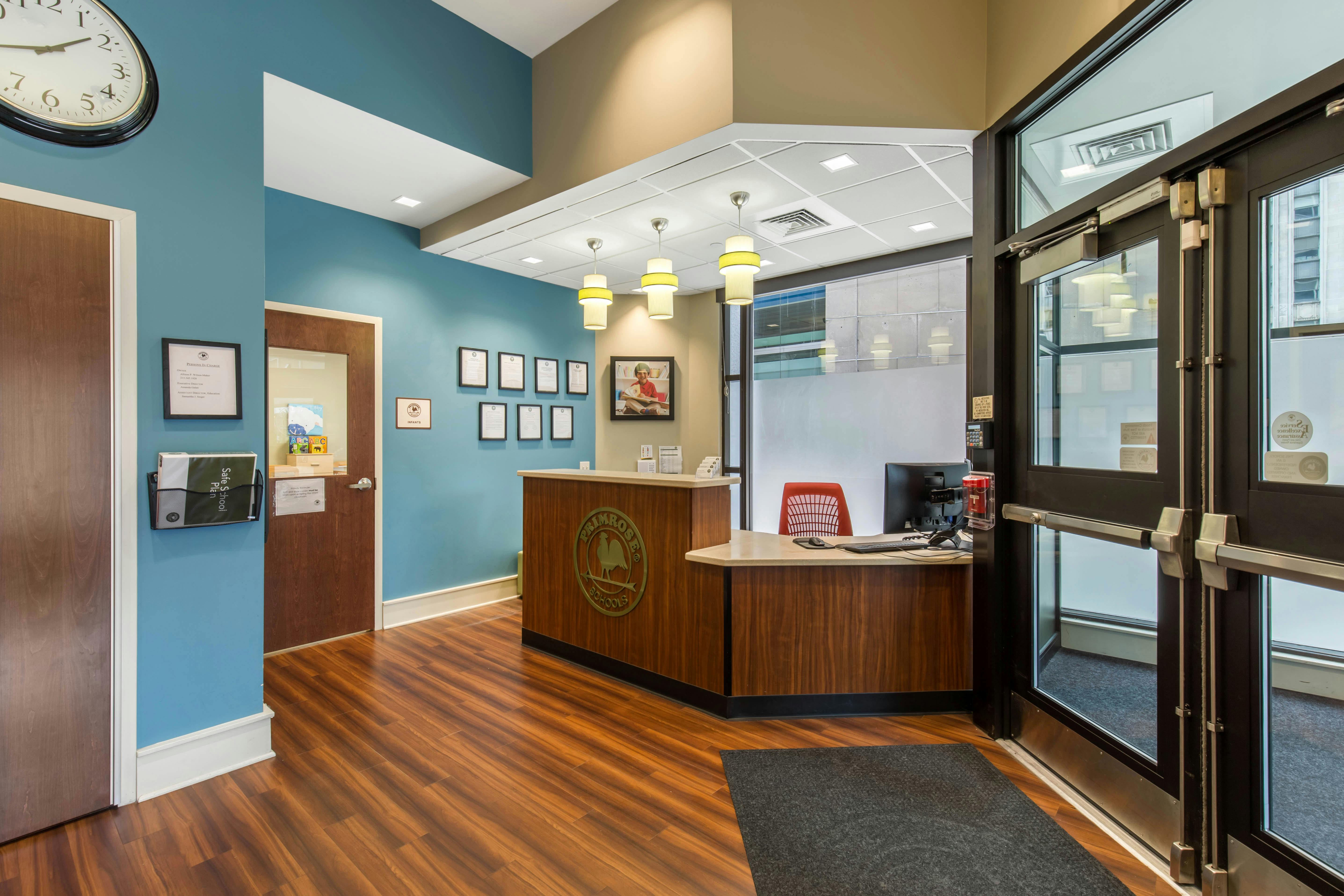 Reception desk with wood paneling and blue walls, glass entrance doors on the right
