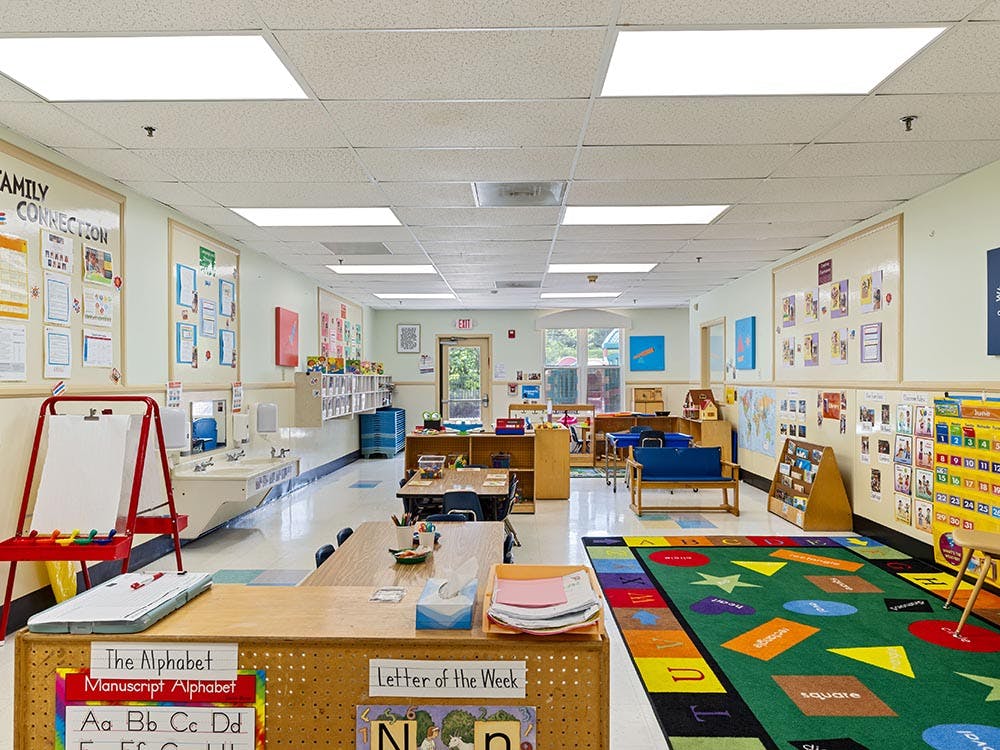 Empty colorful children's classroom with small tables, chairs, and play mats
