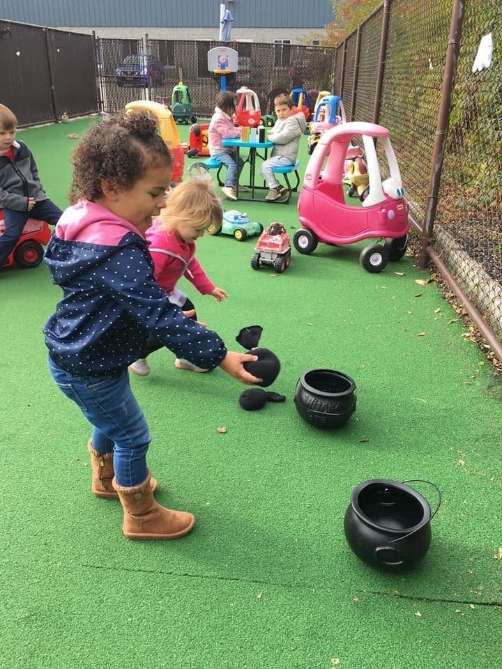 Child playing with black pots and objects on green ground