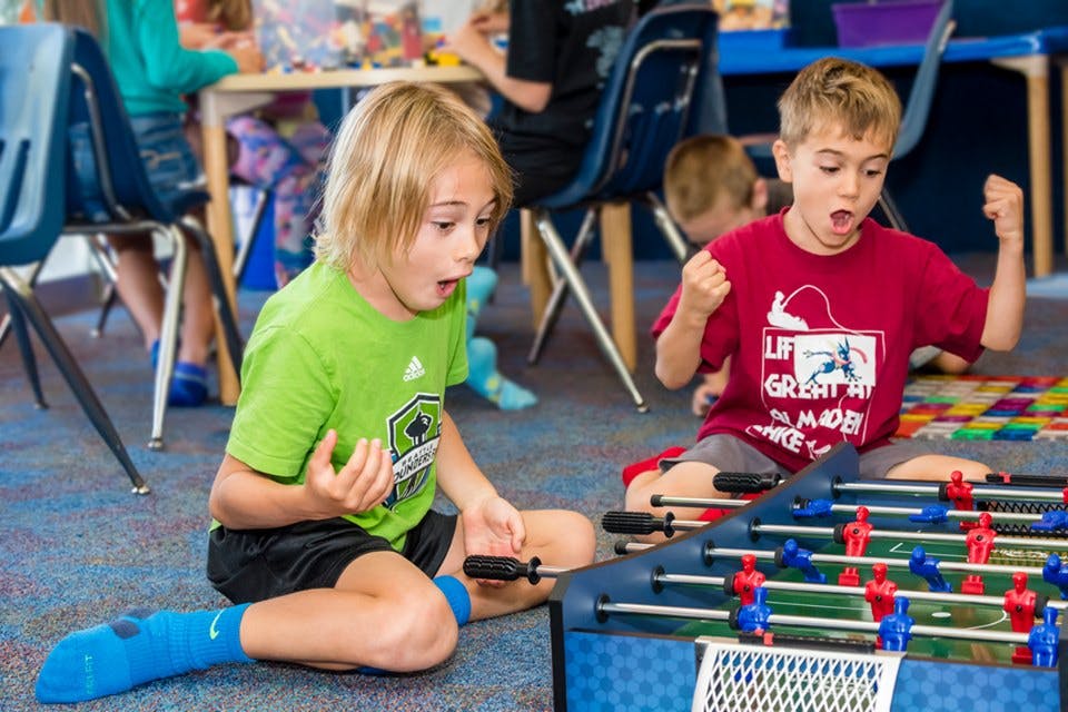 Two children playing foosball on the floor