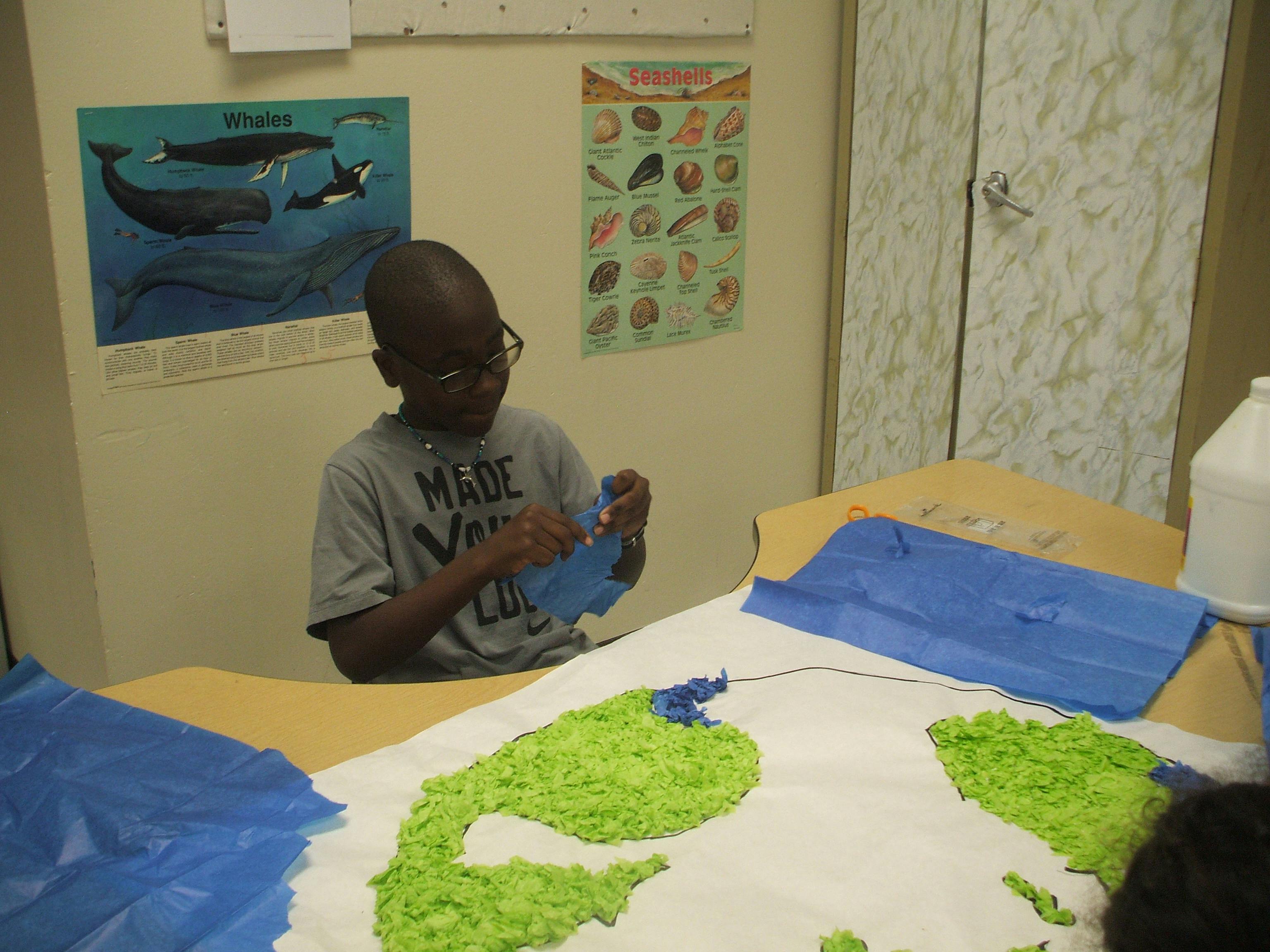 Child making a craft with blue and green paper