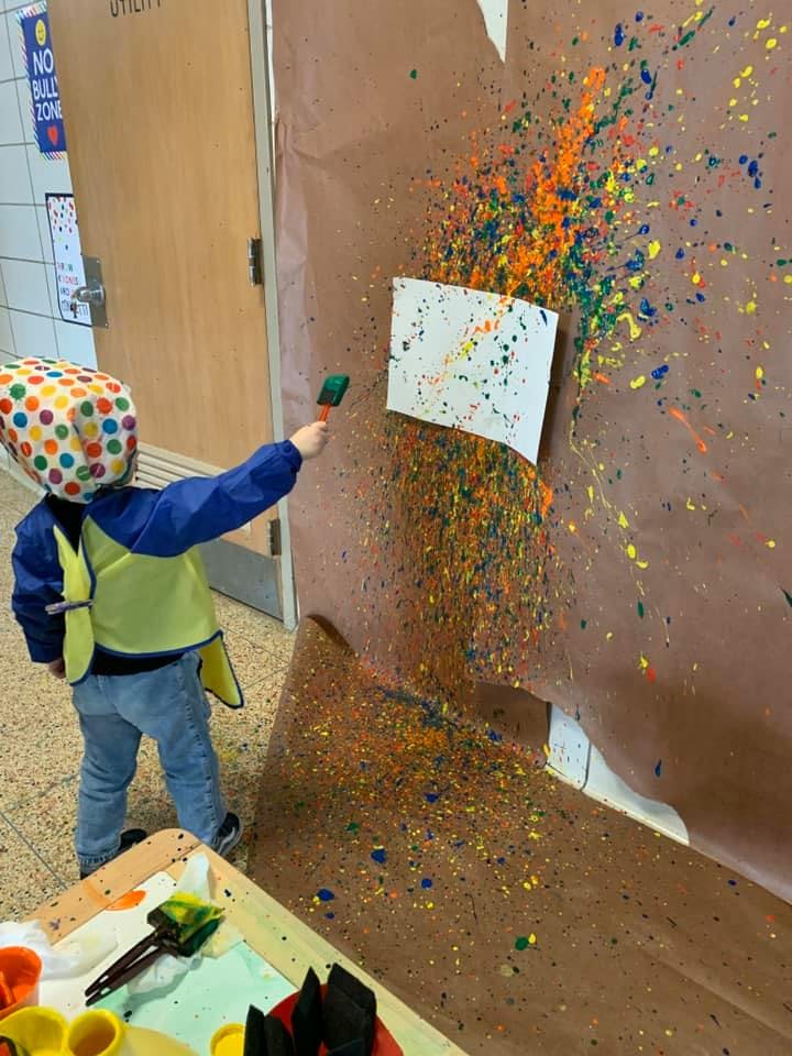 Child splattering paint onto a paper-covered wall