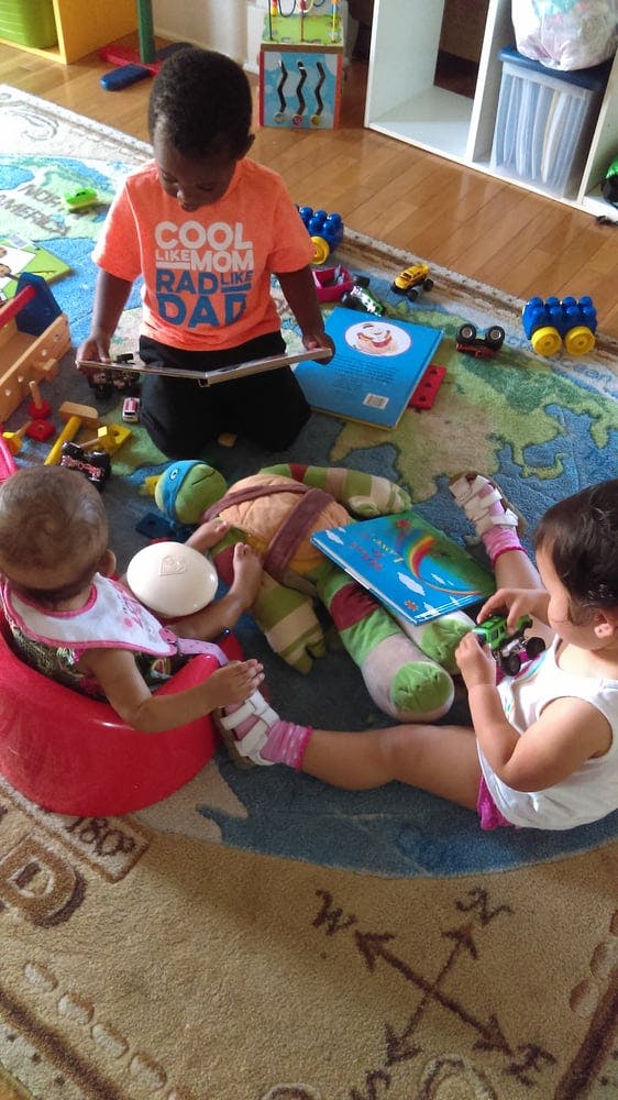 Three children playing with toys on a rug