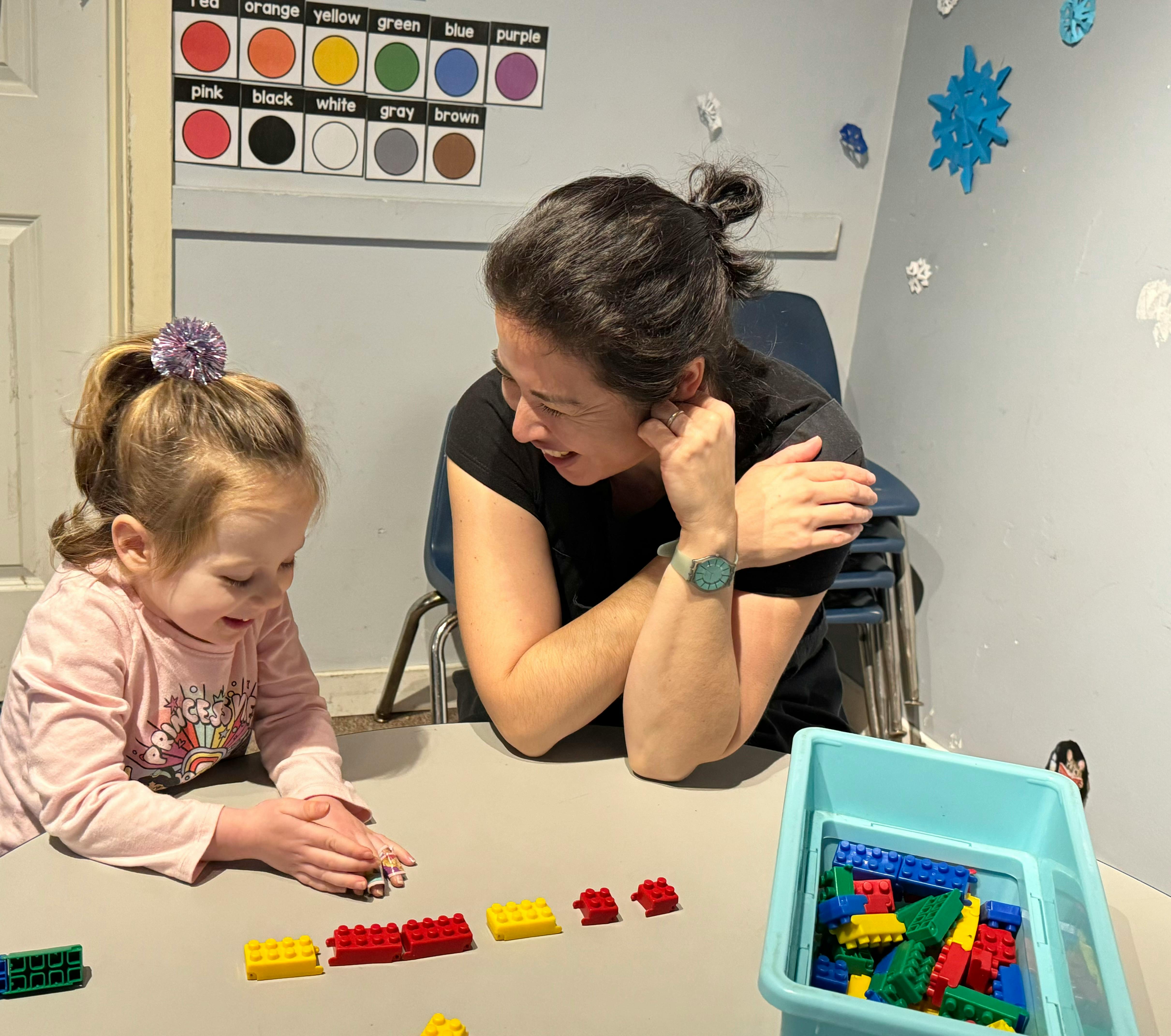 Person and child playing with building blocks at a table