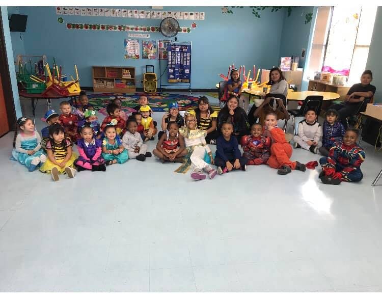 Group of children and adults sitting on the floor in a classroom