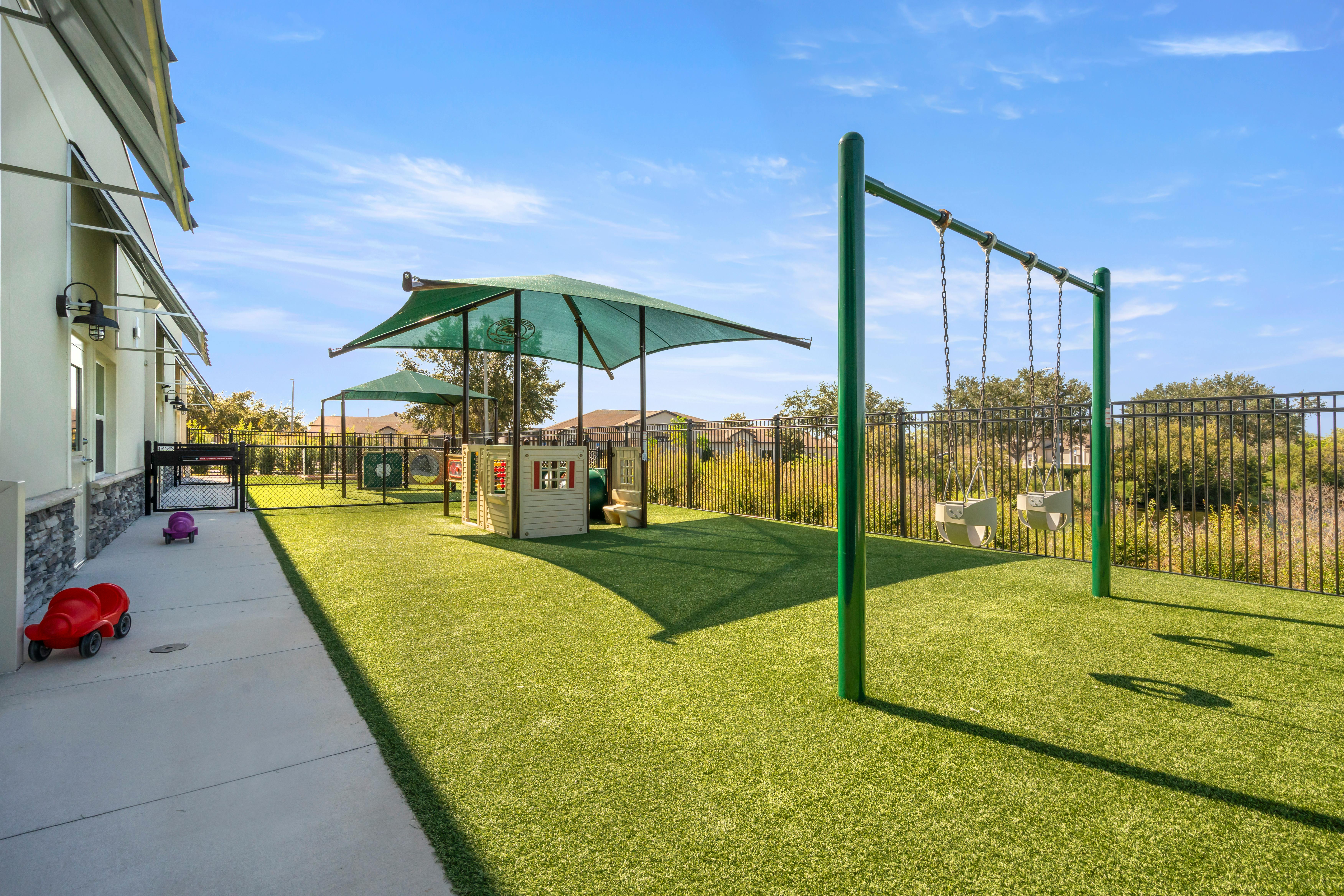 Outdoor playground with artificial turf, play structures, and swing set