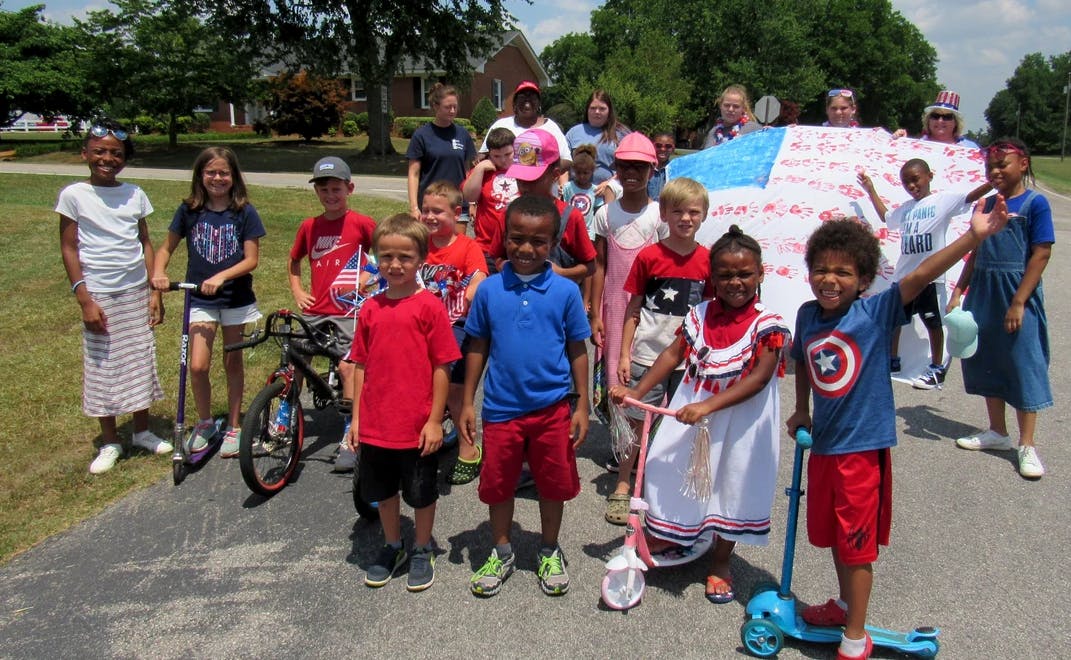 Group of children and adults with a large American flag