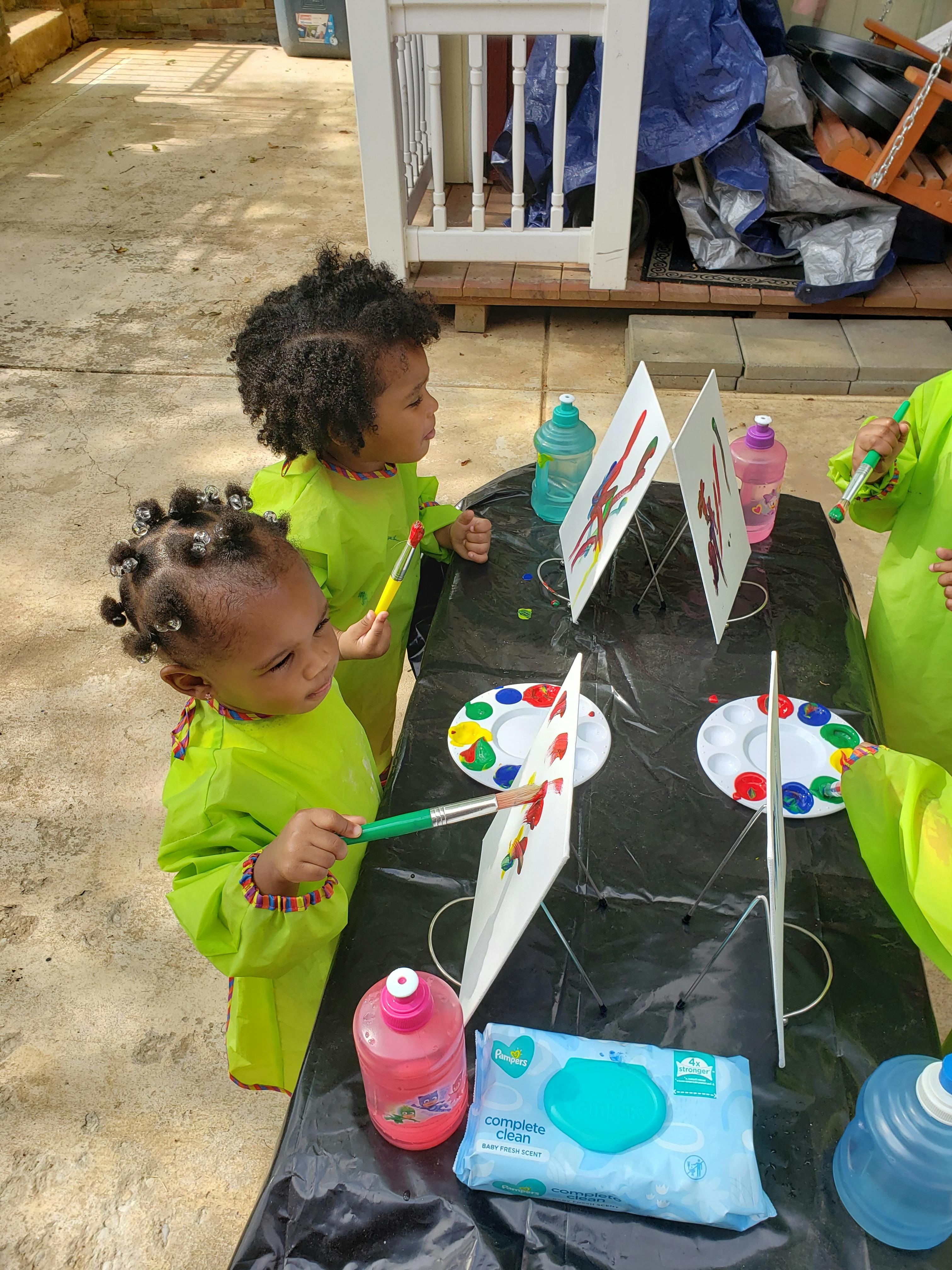 Two children painting at a table with easels and paint palettes