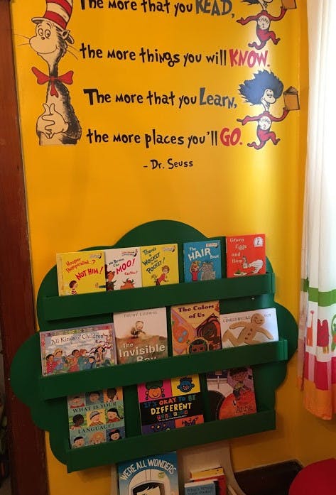 Dr. Seuss quote on a yellow wall above a green bookshelf with children's books
