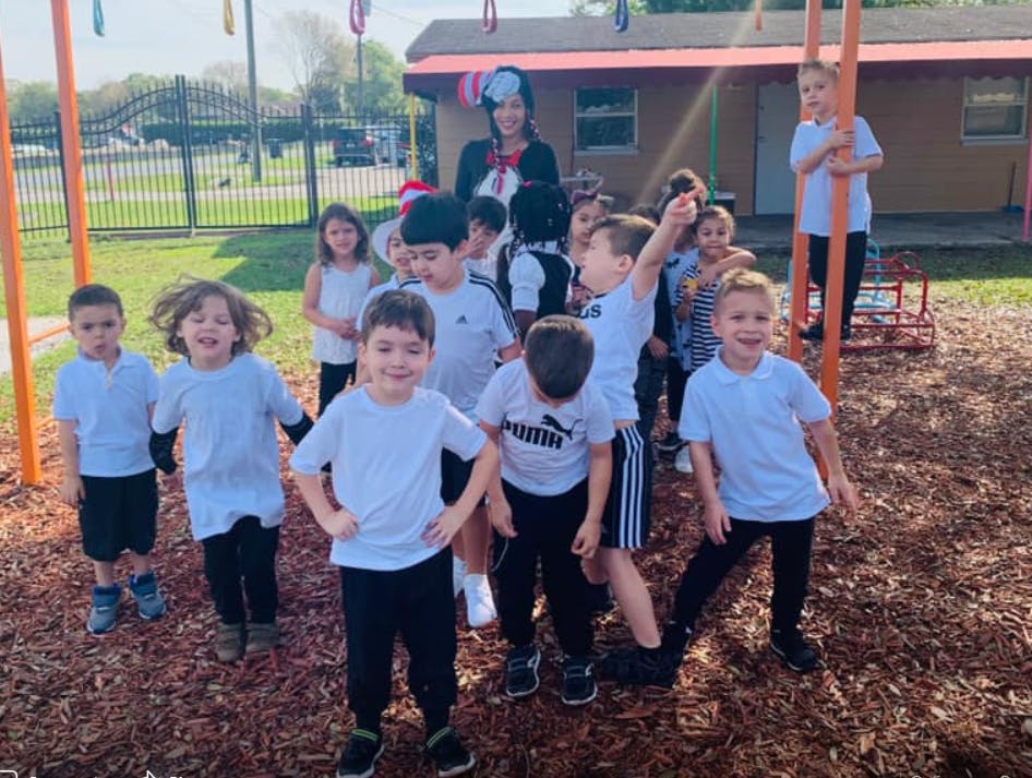 Group of children and an adult standing on wood chips outdoors