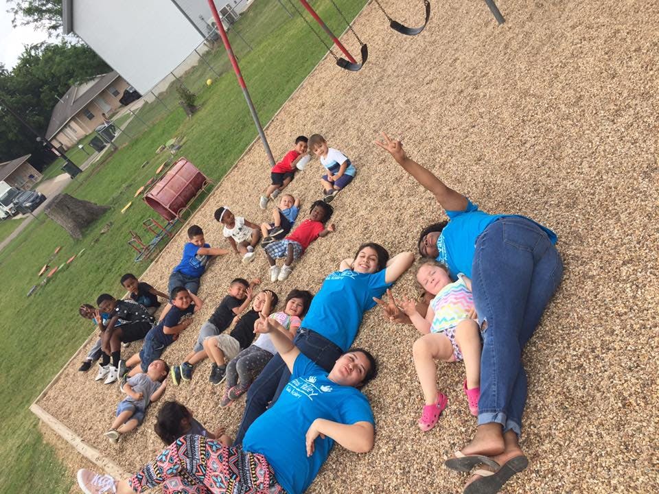 Group of people and children lying on wood chips at a playground
