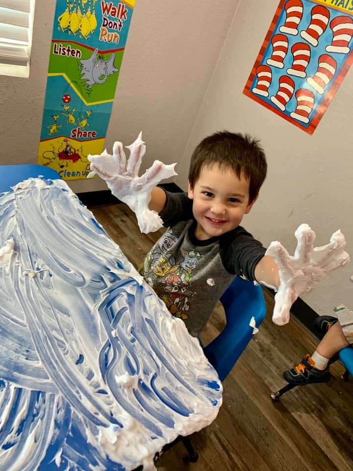 Child with shaving cream on hands and table