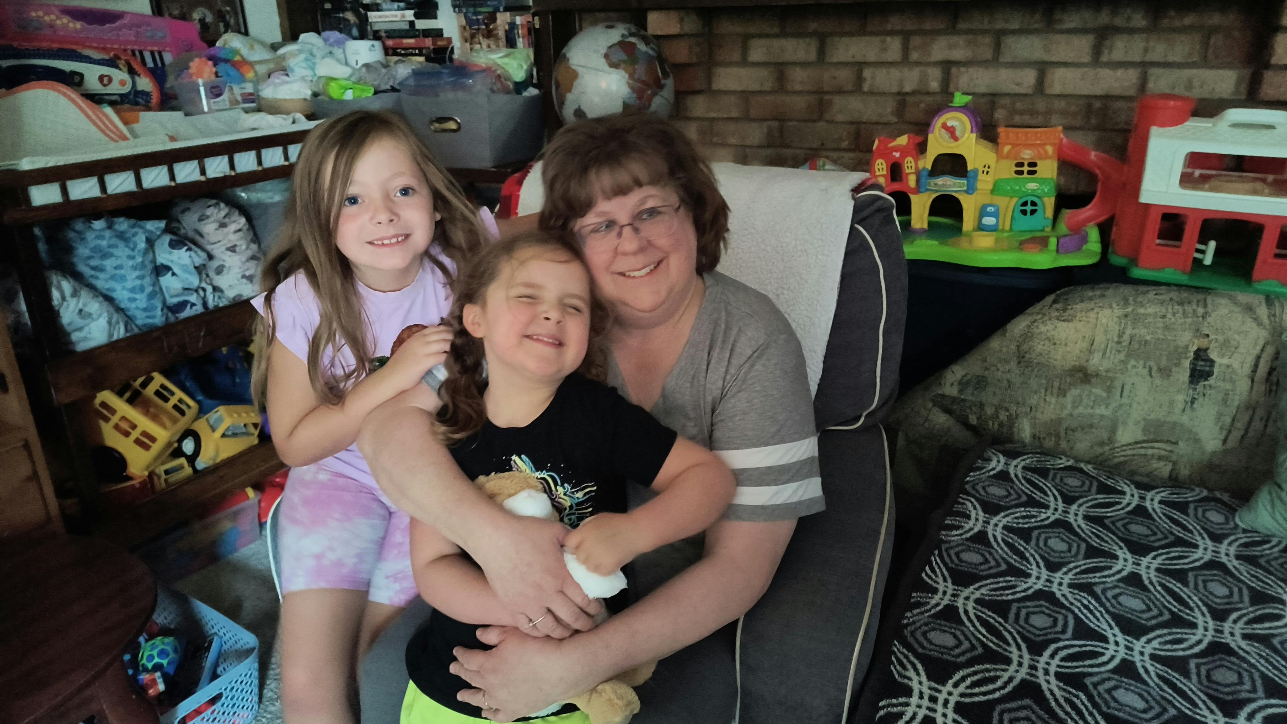 A person sitting in a chair holding two children