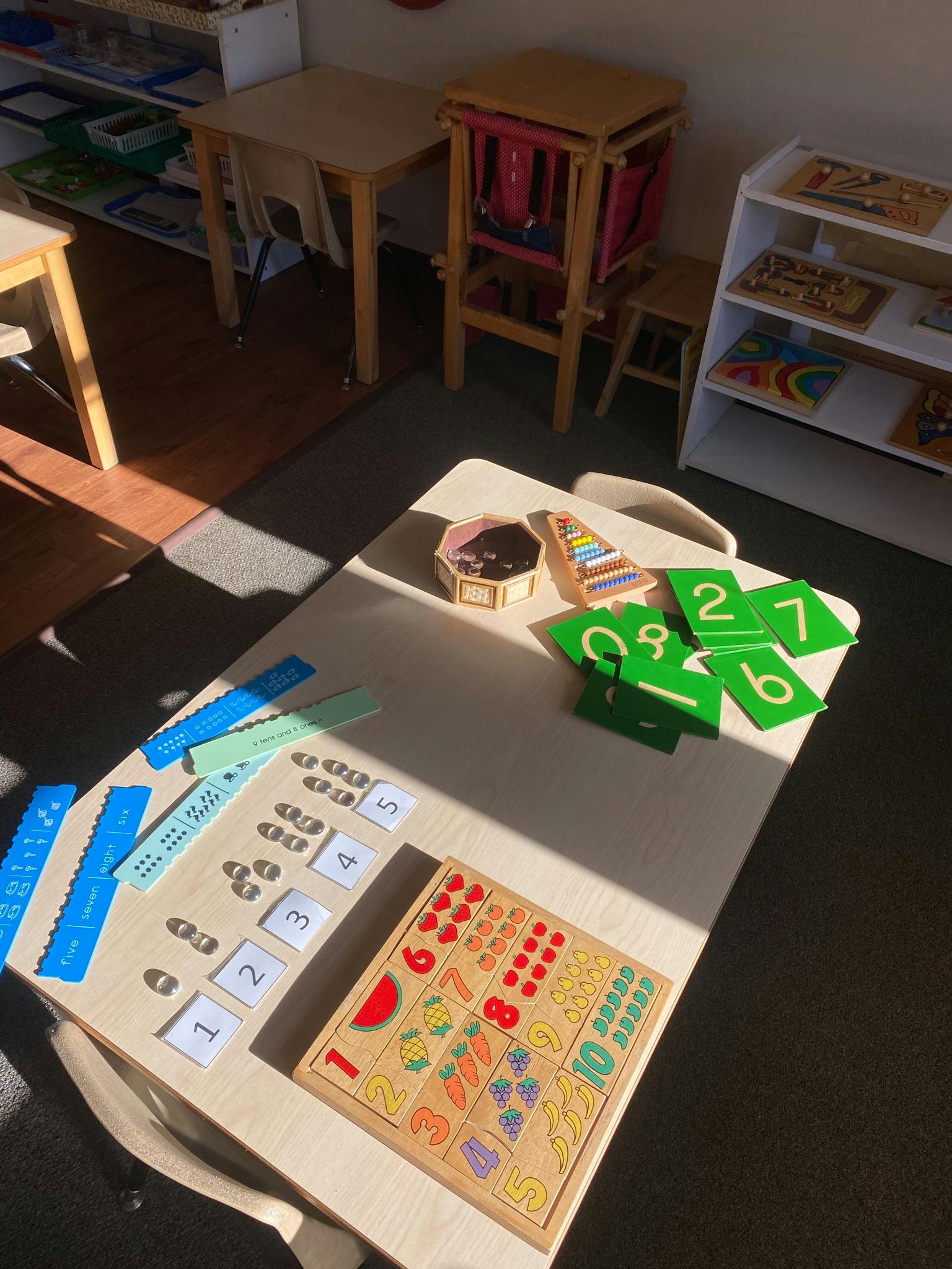 Table with various learning materials including number cards and wooden puzzles