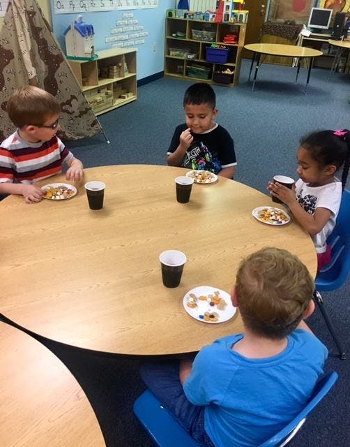 Four children sitting at a round table with plates and cups