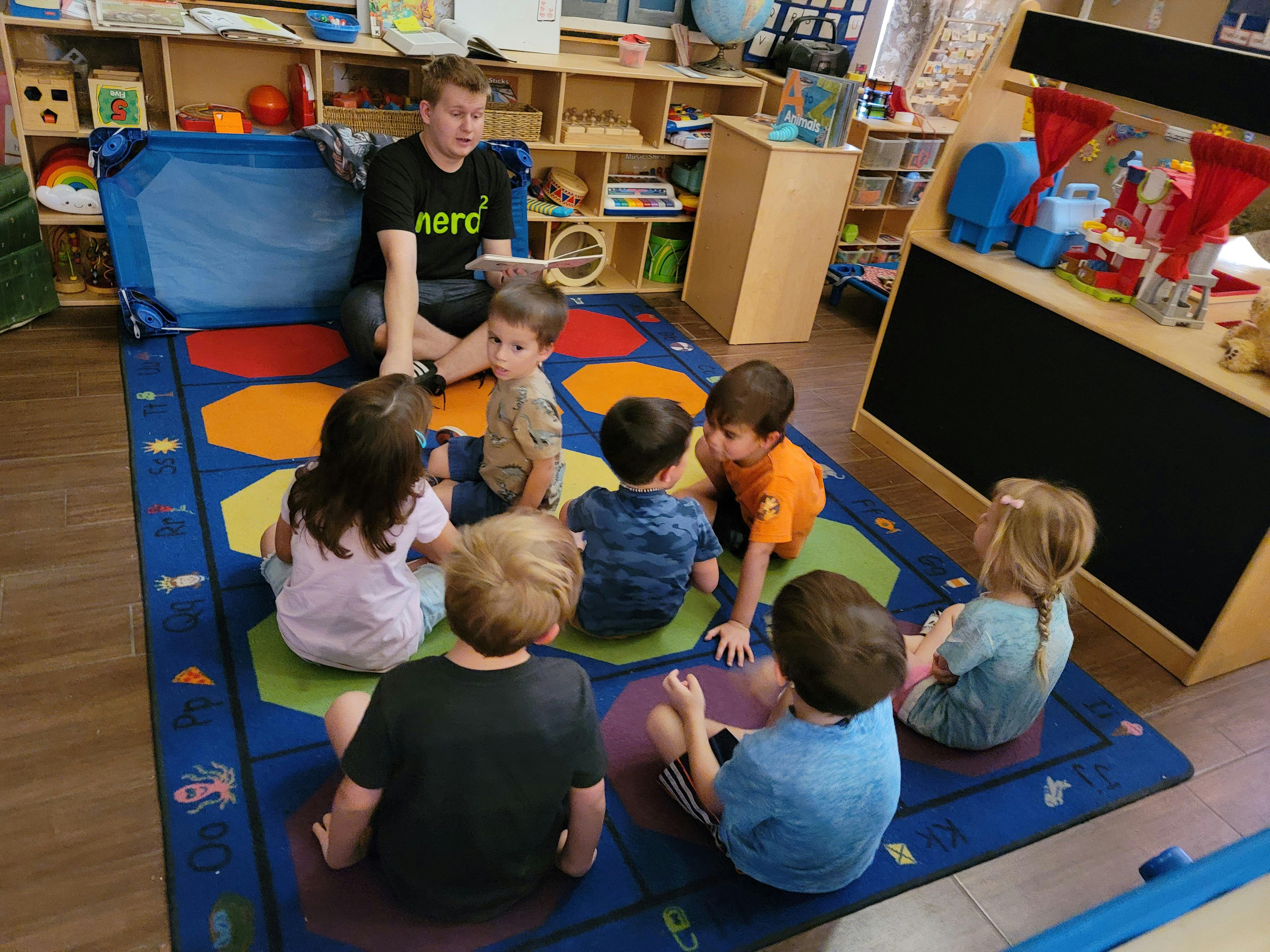 Person sitting on floor with children in a circle