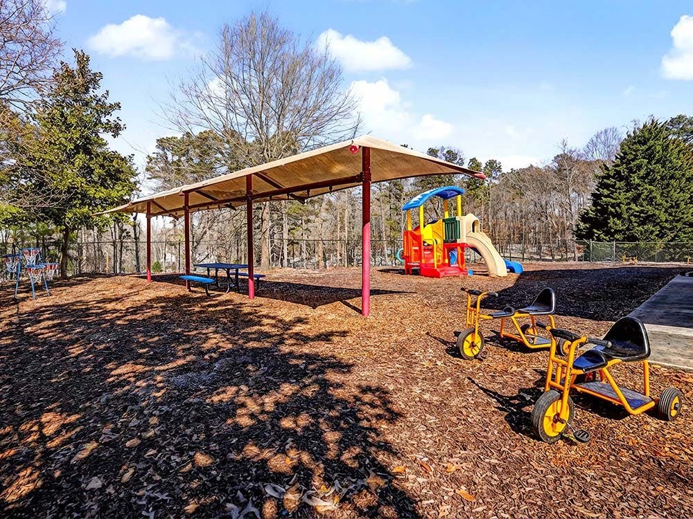 Playground with mulch, a playset, tricycles, and a covered picnic area