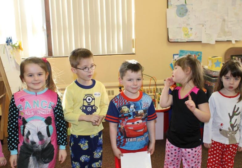 Five children standing in a classroom