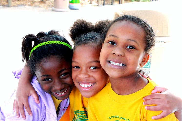 Three smiling children with arms around each other