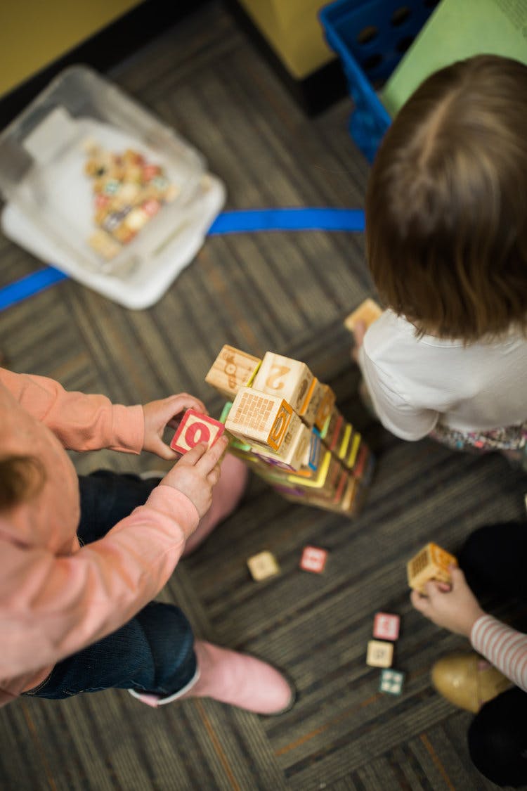 Two children playing with wooden blocks on the floor